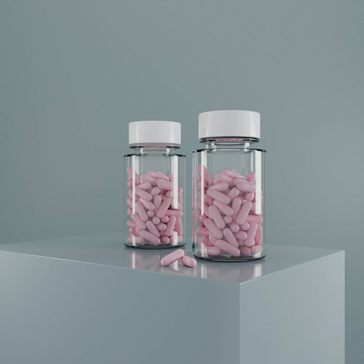 Two pill bottles filled with pink medication.
